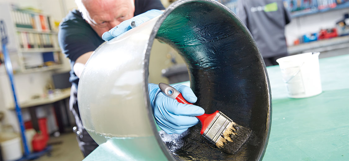Mitarbeiter der Carl Nolte Technik streicht Rohrinnenseite mit dem Pinsel mit Beschichtung ein